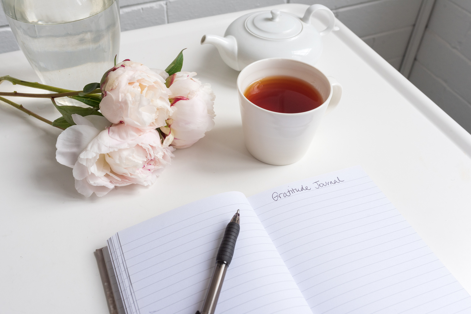 Gratitude journal with peonies and tea on table